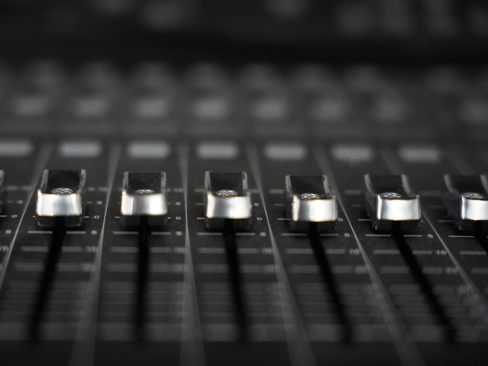 Close‑up of an engineer's hand adjusting a fader on a professional mixing desk.